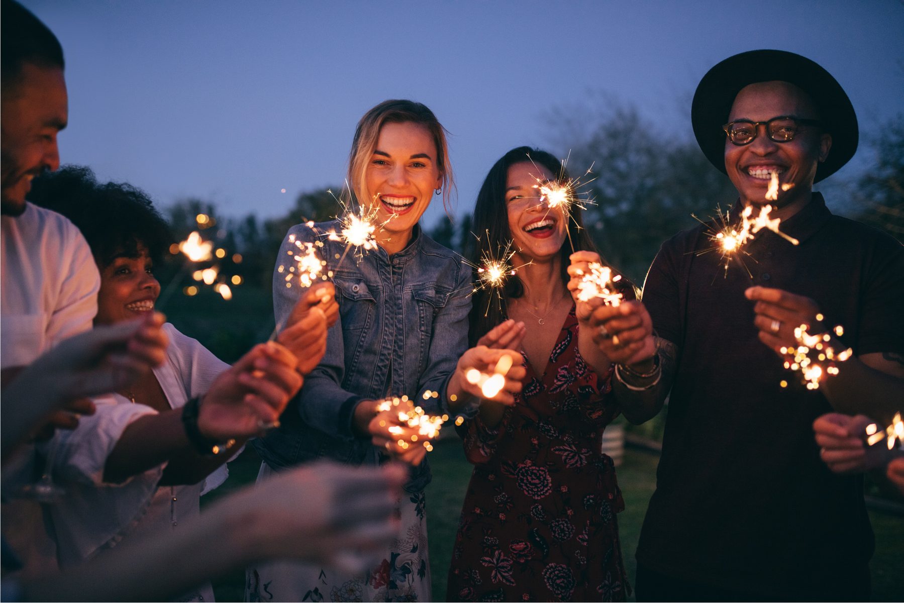 Friends holding sparklers at an evening event