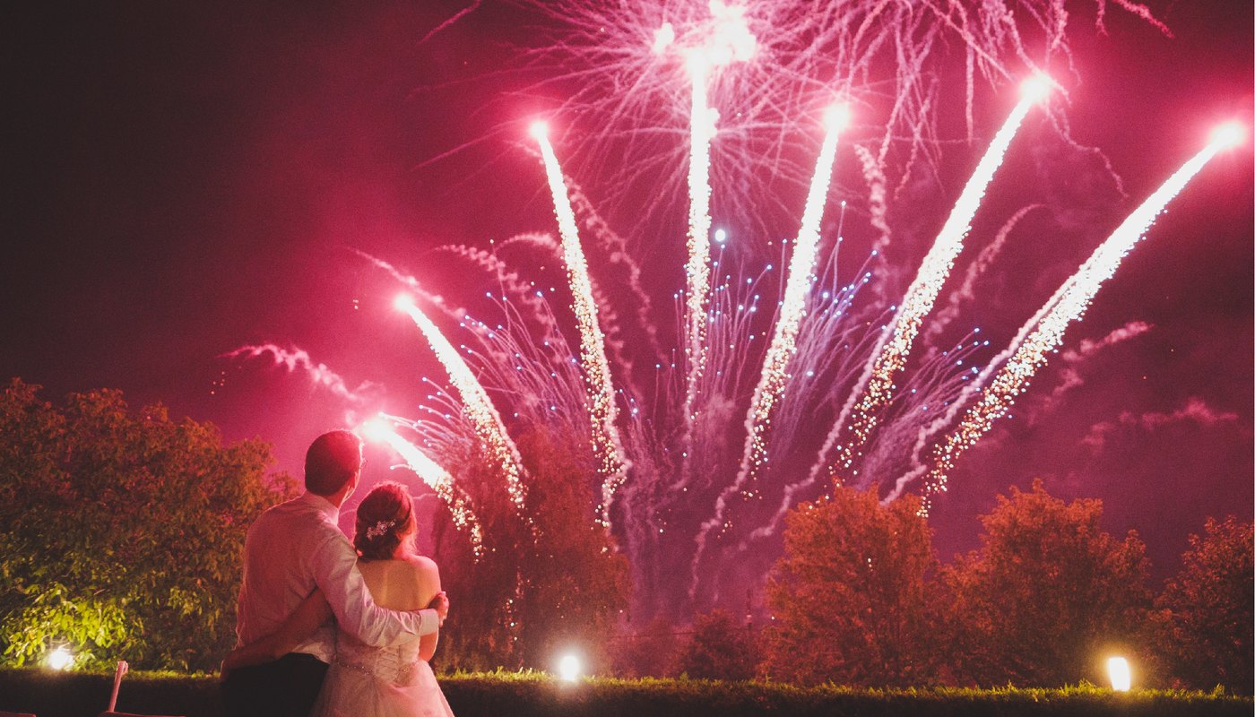 Wedding couple watching a bright professional firework display