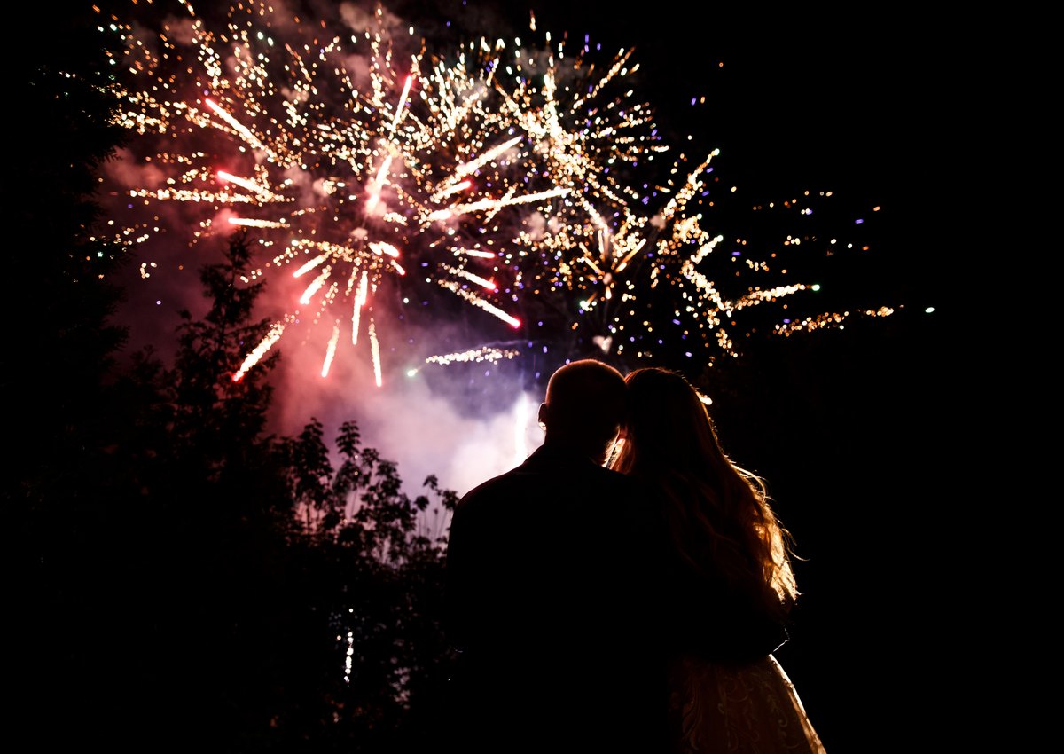 Couple watching wedding fireworks silhouetted against the night sky
